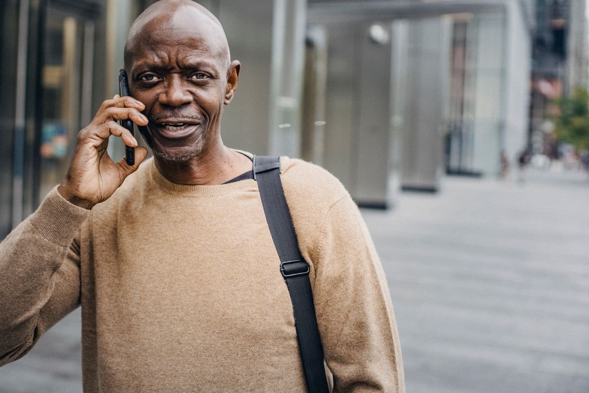 Man smiling during a phone call on a city street