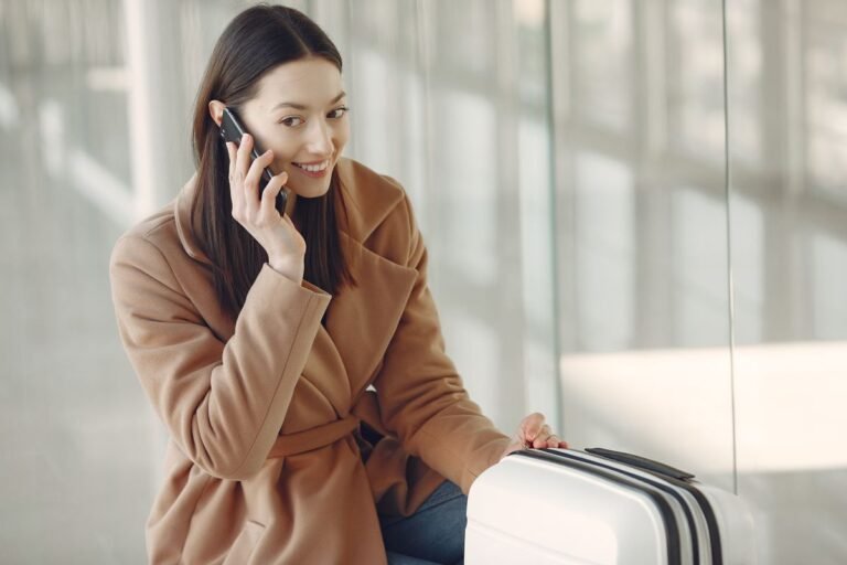 Traveller on a phone call next to her suitcase at the airport