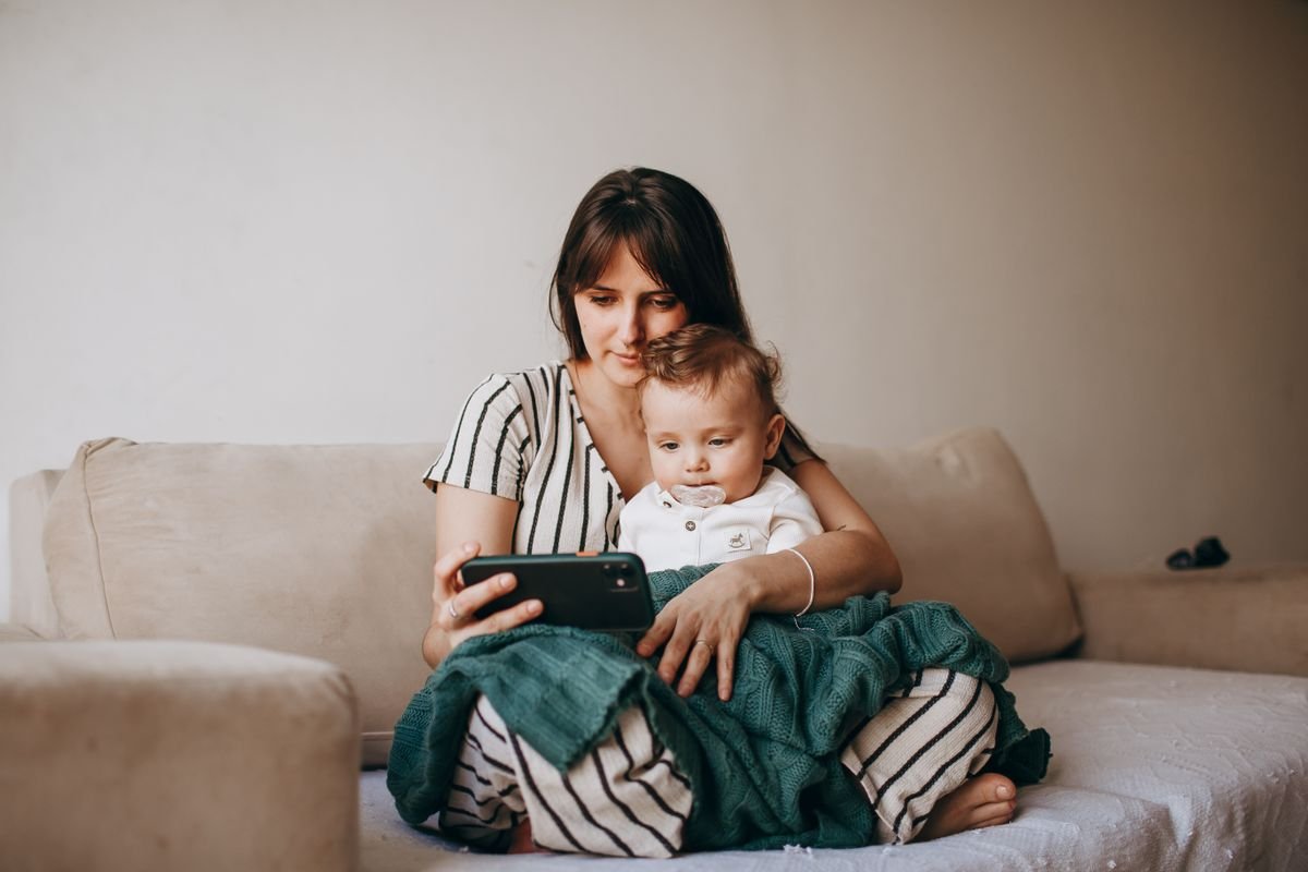 Mother and baby watching a video on a smartphone on the sofa