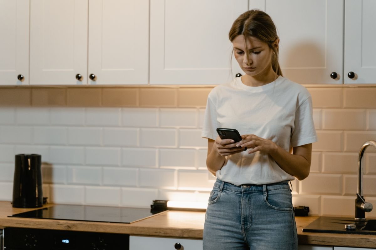 Woman reading a message on her phone in the kitchen