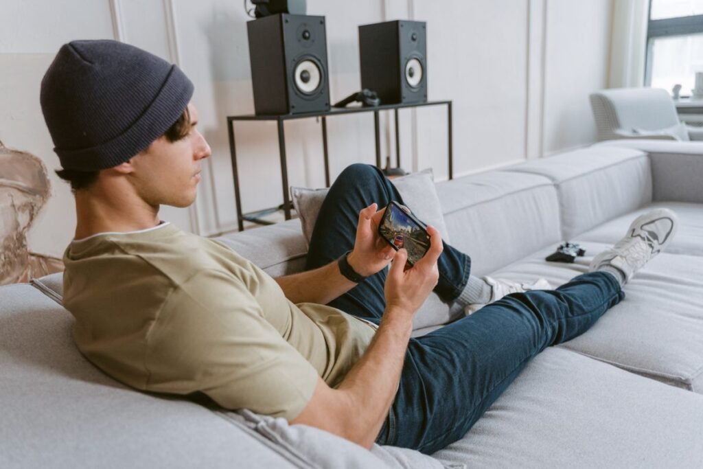 Young man playing a mobile game on his phone on the couch