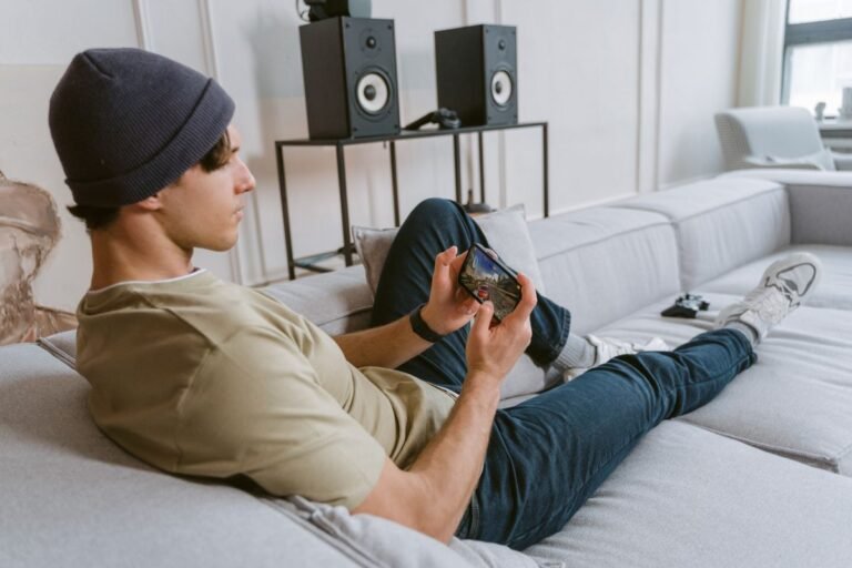 Young man playing a mobile game on his phone on the couch