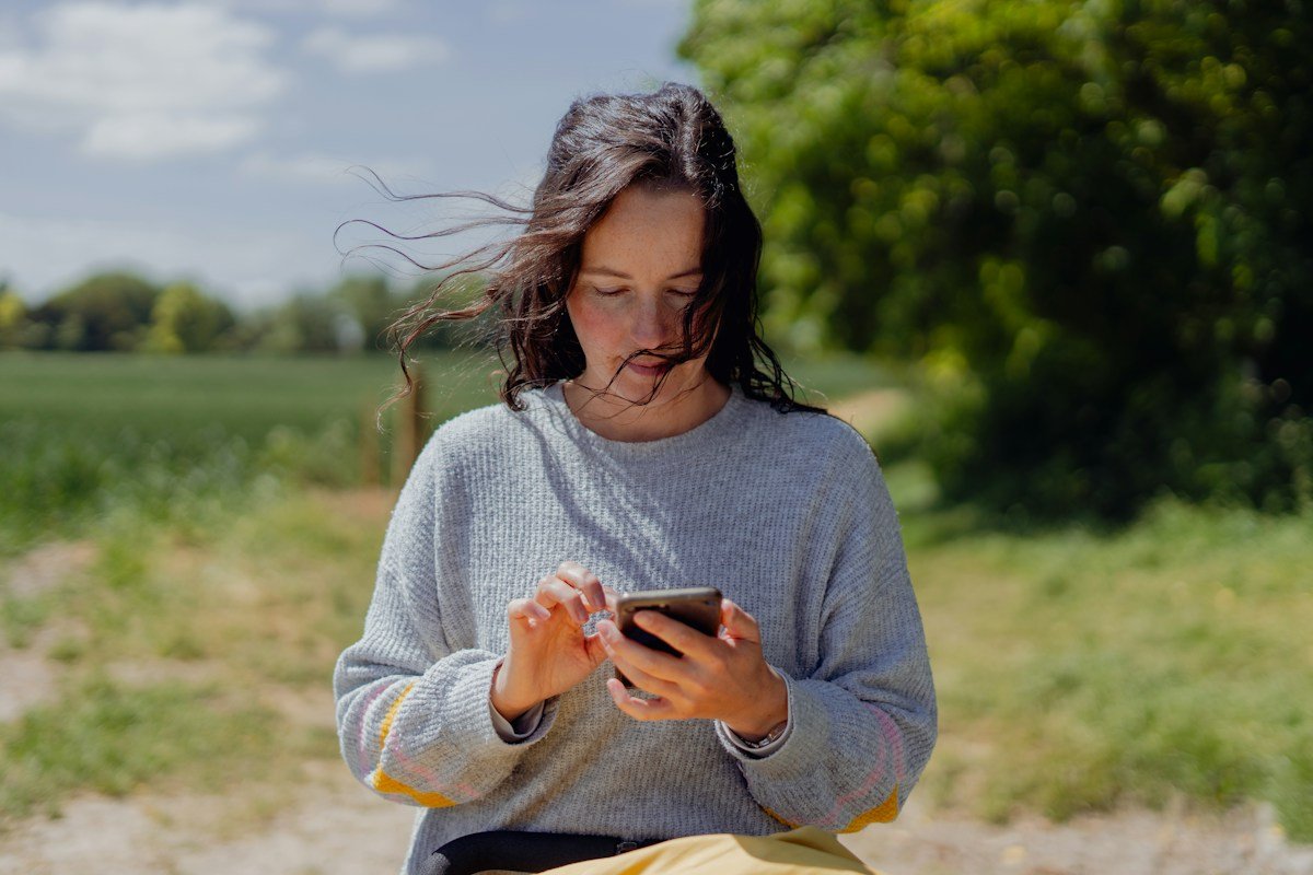 Woman typing a message on her phone outdoors on a sunny day